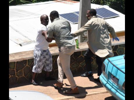 Garfield Winter, a resident of Walkers Hill in Red Hills, St Andrew, falls over a wall after allegedly being pushed by a cop from the St Andrew North Police Division. A member of the police’s forensics unit tried to prevent the man from falling. Winter w
