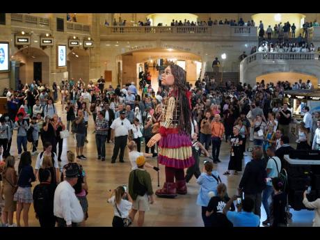 Credit: AP A large puppet named Little Amal walks around Grand Central Station in New York.