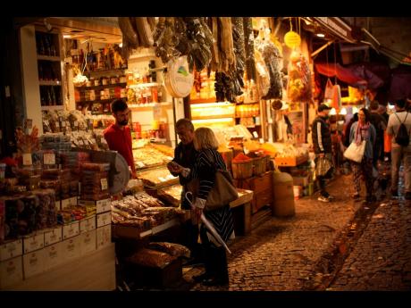 Credit: Francisco Seco A food shop seller talks to clients in a street market in Istanbul, Turkey, Thursday, on September 22. The depreciation of Turkey’s national currency is likely to intensify the financial worries of residents who have seen their purchasing power erode dur