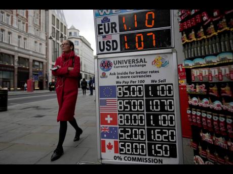 Credit: AP A woman walks past a sign that shows the exchange rate at a bureau de change in London, Tuesday, September 27, 2022.