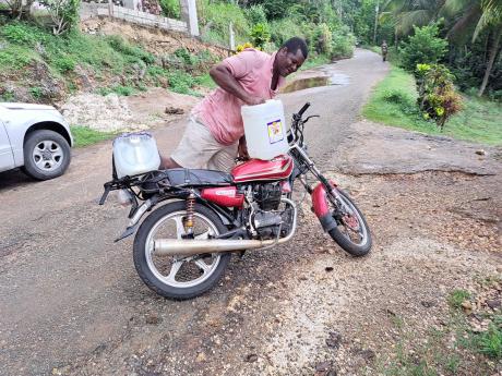 Resident Ray Brown lifts a container of water from his motorcycle.