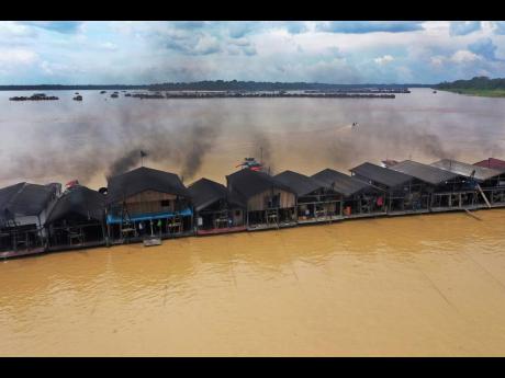 
Dredging barges, operated by miners illegally mining gold, converge on the Madeira River, a tributary of the Amazon river in Autazes, Amazonas state, Brazil, on November 25, 2021.