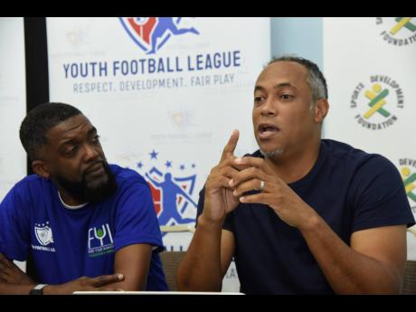 Credit: Ian Allen Andre Virtue (right), CEO, Ballaz International Group, conducting a clinic for coaches in the Junior Cup football competition. Looking on is Shaun Williams, member of the organising committee, Junior Cup. The clinic took place at the launch of the Junior