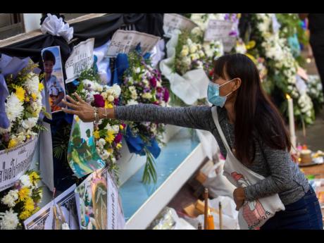 A woman touches a photo of the victims of a mass killing attack outside Wat Rat Samakee temple in Uthai Sawan, northeastern Thailand.