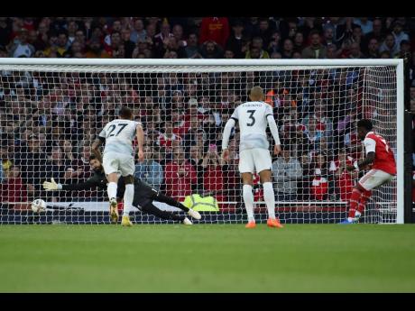 Arsenal’s Bukayo Saka (right) scores a penalty kick past Liverpool’s Alisson Becker during yesterday’s  English Premier League  match at Emirates Stadium in London. Arsenal won 3-2.