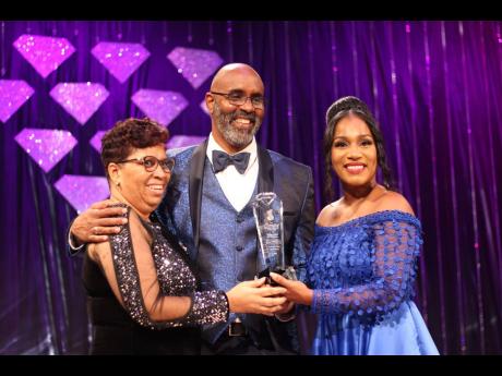 Charmaine Wilkinson (left), wife of radio broadcaster Nigel Wilkinson, is invited on stage as her husband is presented with the Sterling Award for Excellence by Basillia Barnaby-Cuff.