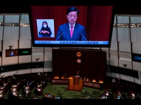 A video screen shows Hong Kong Chief Executive John Lee as he delivers his policy address at the chamber of the Legislative Council in Hong Kong on Wednesday, October 19.