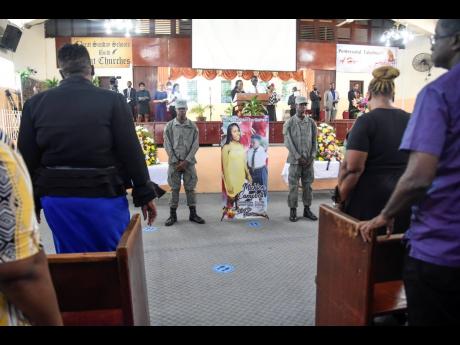 Two members of the Kingston Technical High School Cadet Corps stand beside a banner in honour of their late schoolmate, Michion Campbell, during a memorial service at the Pentecostal Tabernacle on Wildman Street in Kingston on Friday.