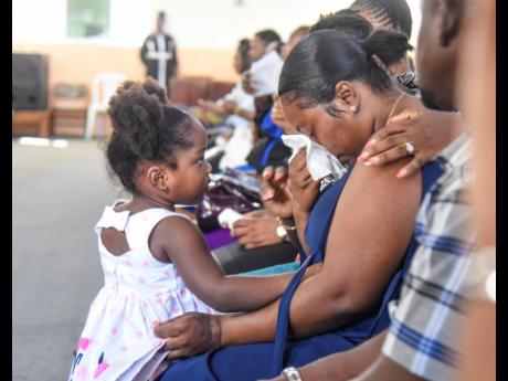 Daughter Lola (left) comforts a grieving Vanessa Clarke, mother of Michion Campbell, as she uses a hand towel to dry her tears during a memorial service for the late Kingston Technical High School student, who was stabbed to death by a schoolmate last mont