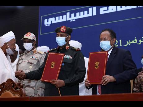In this photo provided by the Sudan Transitional Sovereign Council, Sudan’s top general Abdel Fattah Al-Burhan (centre) and Prime Minister Abdalla Hamdok hold documents attended by General Mohammed Hamdan Dagalo (second left) during a ceremony to reinsta