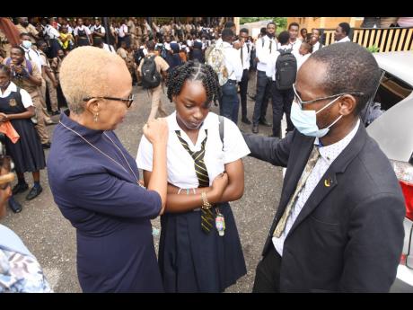 Minister of Education Fayval Williams (left) speaks with Kayanna Lawrence, a grade 11 student and friend of 16-year-old Michion Campbell, who was stabbed to death, and Maulton Campbell, principal, during a visit at Kingston Technical High School on October
