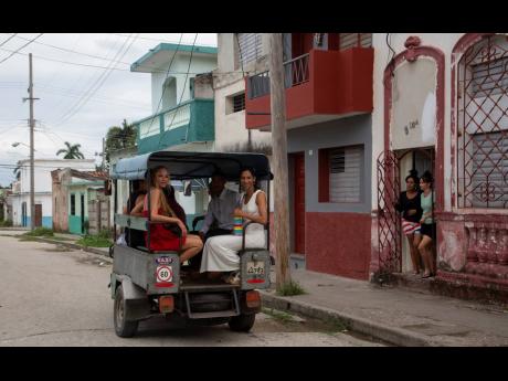 Brides Lisset Diaz Vallejo (left) and Liusba Grajales travel in a taxi to the notary office to get married in Santa Clara, Cuba, on October 21.