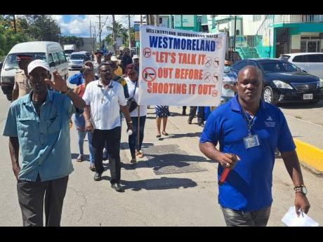 Bishop Oneil Russell (right), head of the Ark of the Covenant Holy Trinity Church in Westmoreland, leads a group of residents, police officers and members of the Restorative Justice Centre in a peace march through sections of Savanna-la-Mar on Thursday.