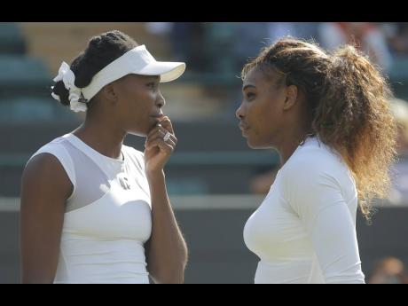 Venus Williams (left) and sister Serena Williams talk between points in their women’s doubles match in London in July 2014.