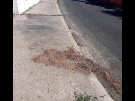 Dirt covers the blood-splattered roadway where two of the three men killed by gunmen along Lincoln Crescent, Kingston 5, fell Friday evening. Gunmen travelling in a Mazda motor car reportedly sprayed the area with bullets, killing the trio and injuring one