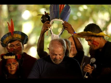 Brazil’s former president who was running for reelection, Luiz Inacio Lula da Silva, receives a headdress from Assurini Indigenous people during a meeting with traditional populations from the Amazon in Belem, Para state, Brazil, September 2, 2022. In a 