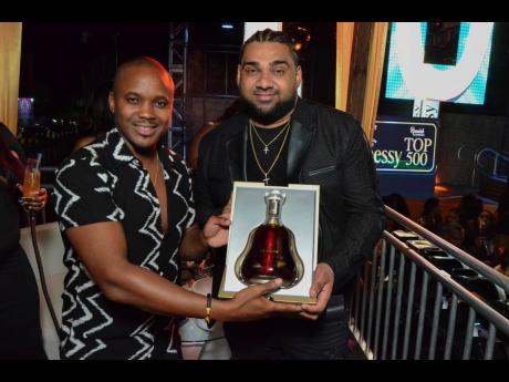 Credit: Contributed Kamal Powell (left), regional marketing manager for J. Wray & Nephew, presents Romeich with a special bottle of Hennessy Paradis.