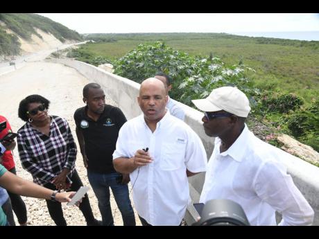 Minister without Portfolio in the Ministry of Economic Growth and Job Creation, Everald Warmington (right), and Member of Parliament for St Thomas Western, James Roberts (second right), address journalists at a section of the Southern Coastal Highway Impro