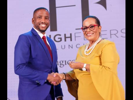 Nobi Robinson (left) receives his High Flyer gold pin from Dale Greaves-Smith, branch manager, Sagicor Life Mandeville.
