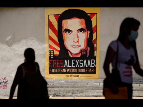 Pedestrians walk near a poster asking for the freedom of Colombian businessman and Venezuelan special envoy Alex Saab, in Caracas, Venezuela, September 9, 2021.