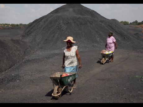 Women from the Masakhane township push wheelbarrows atop a coal mine dump at the coal-powered Duvha power station, near Emalahleni (formerly Witbank), east of Johannesburg.