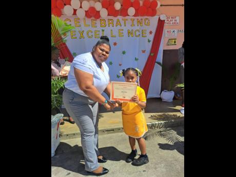 Sophia Thomas, a teacher at Portsmouth Primary School, presents a certificate of excellence to Gabrielle Smith.