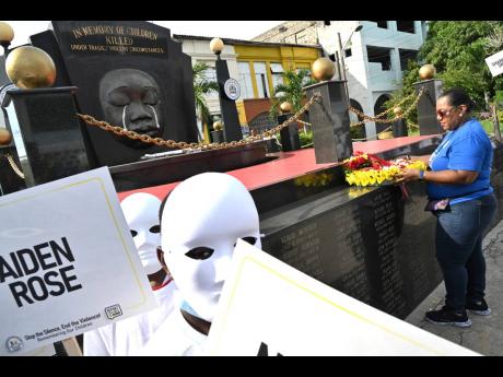 Rosalee Gage-Grey, CEO of the Child Protection and Family Services Agency, lays a wreath at the monument in downtown Kingston that commemorates children who died violently.