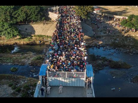 Credit: AP Haitians wait to cross the border between Dominican Republic and Haiti in Dajabon, Dominican Republic, on Friday, November 19, 2021.