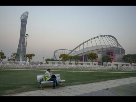 A migrant worker sleeps on a bench before his early-morning shift, in front of Khalifa International Stadium, also known as Qatar’s national and oldest stadium, on Saturday, October 15.