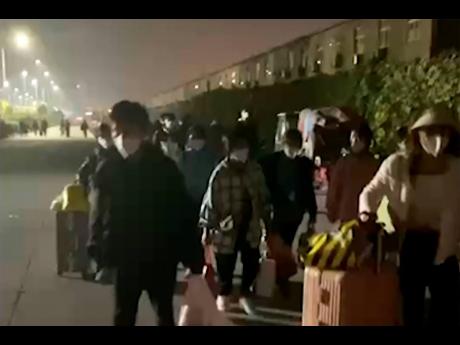 In this photo taken from video footage and released by Hangpai Xingyang, people with suitcases and bags are seen leaving  a Foxconn compound in Zhengzhou in central China’s Henan Province on October 29, 2022. 