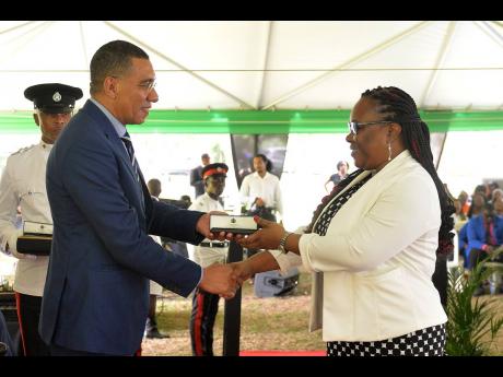 Prime Minister Andrew Holness (left), presents an award to Cameel Francis for over 25 years of service to Tax Administration Jamaica during the Jamaica Civil Service Long Service Awards Ceremony, held on the lawns of King’s House on November 23.