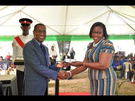 Minister of Finance and the Public Service Dr Nigel Clarke presents an award to Donna Dawkins for over 25 years of service to the Western Regional Health Authority during the Jamaica Civil Service Long Service Awards Ceremony, held on the lawns of King’s
