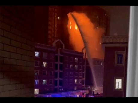 In this image taken from video, firefighters spray water on a fire at a residential building in Urumqi in western China’s Xinjiang Uyghur Autonomous Region on Thursday.