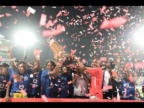 President of the Inter-Secondary Schools Sports Association Keith Wellington (right) presents the Manning Cup to members of the Jamaica College team shortly after they defeated St Andrew Technical 8-7 on penalties in the final at Sabina Park last night.