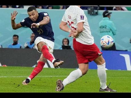 France's Kylian Mbappe (left) scores his their second goal during the World Cup round of 16 football match against Poland, at the Al Thumama Stadium in Doha today. France won 3-1.