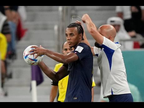 An assistant coach takes of the necklace of France's Jules Kounde during the World Cup round of 16 football match against Poland, at the Al Thumama Stadium in Doha, Qatar today. France won 3-1.
