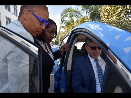 From left: Christene Gittens, senior director, HEART NSTA Trust, Dionne Nugent, chairman of the eDrive Project Steering Committee, and Roberto Aiello, principal regional energy specialist at IDB Lab, check out an electric car on display at the eDrive launc