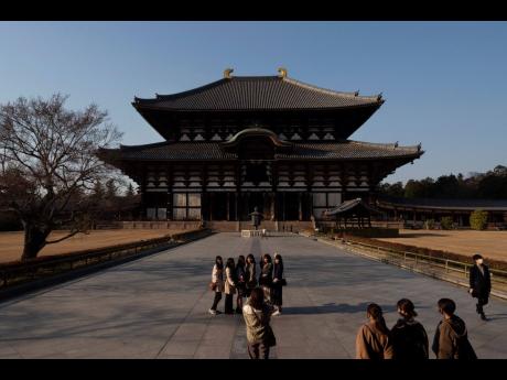 Tourists pause for photos in front of Todaiji temple’s main hall in Nara, Japan, March 17, 2020.