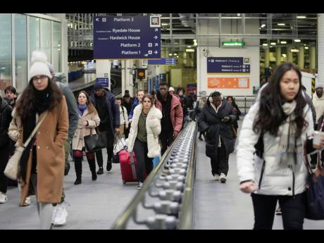 Passengers arrive at the Euston railway station as the members of rail workers stage a strike in London.