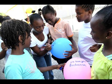 Credit: Rudolph Brown/Photographer Students of Dupont Primary write the name of the late Brehanna Sindale on balloons on the Olympic Way compound of the school on Monday.