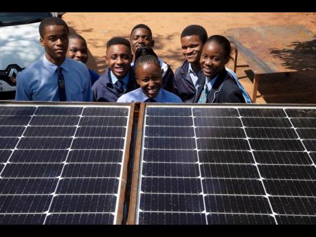 Students from the Soshanguve Automotive School of Specialisation pose for a photograph behind solar panels on a train roof, north of Pretoria, South Africa, on Monday, November 14.