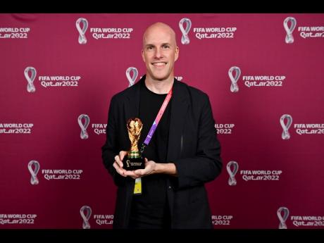 
Grant Wahl smiles as he holds a World Cup replica trophy during an award ceremony in Doha, Qatar, on November 29, 2022. 