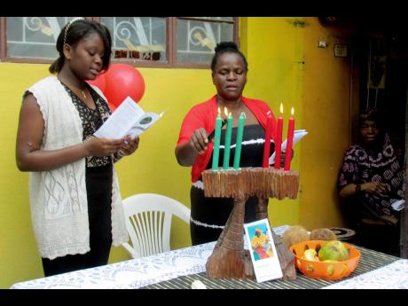 Credit: File In this file photo, people participate in Kwanza activities at the home of Queen Mother Mariamne Samad (right) in January 2018. Samad has since died.