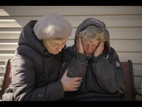 A neighbour comforts Natalia Vlasenko, whose husband, Pavlo Vlasenko, and grandson, Dmytro Chaplyhin, were killed by Russian forces in Bucha, Ukraine.