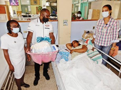 Tristan Stewart (second left) of Kirk FP offers kind words to Peta-Gay Barnaby and her baby while Sister Fay Reid (left) of the St Ann’s Bay Regional Hospital and Tanecia Lacey (right) of the Registrar General's Department (RGD) look on. Barnaby gave bir