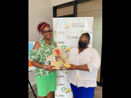 Director of Health Promotion and Protection  at the Ministry of Health and Wellness,Dr Simone Spence (left),  presents a token of appreciation to Knox Junior School teacher Apryl Taylor.