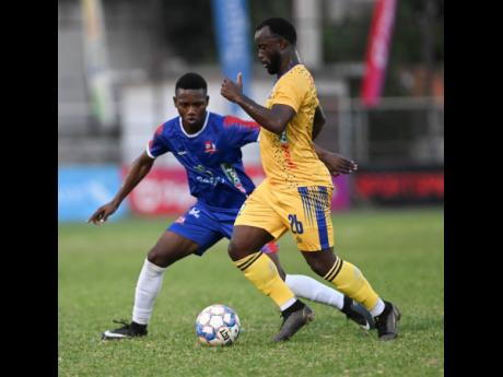Credit: Ricardo Makyn Dunbeholden’s Zackiya Wilks (left) stays close to Molynes United’s Jason Wright during yesterday’s Jamaica Premier League encounter at the Anthony Spaulding Sports Complex. Molynes won 1-0.