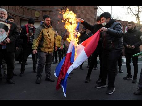 Demonstrators set fire to French flags during their gathering to protest against the publication of offensive caricatures of the Iranian Supreme Leader Ayatollah Ali Khamenei in the satirical magazine Charlie Hebdo, in front of the French Embassy in Tehran