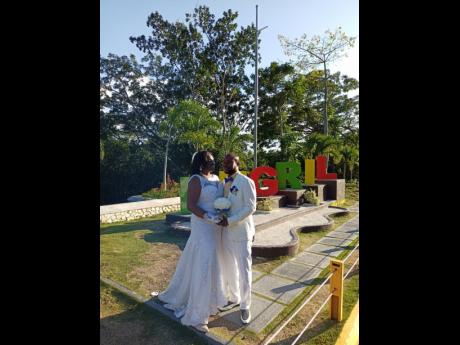 The newly-wed Stewarts stop by the Negril sign to take photos on Wednesday as they celebrated their nuptials. The empty light poles can be seen in the background after thieves made off with three solar-powered lamps.