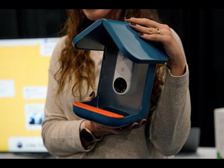 An exhibitor holds up the Bird Buddy smart camera bird feeder during CES Unveiled. The AI-powered camera bird feeder notifies you when a bird is feeding, takes pictures and organises the photos.